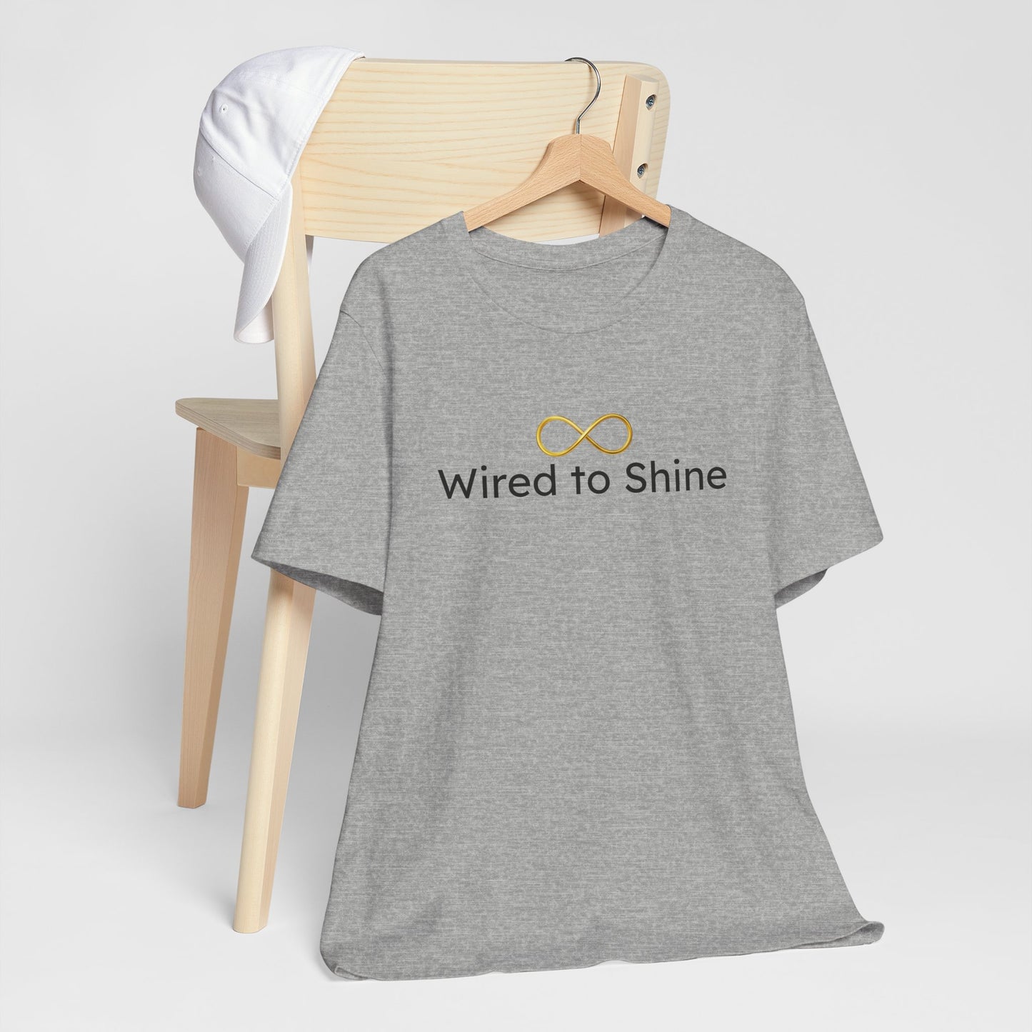 Gray t-shirt with 'Wired to Shine' text and infinity symbol on a wooden chair.
