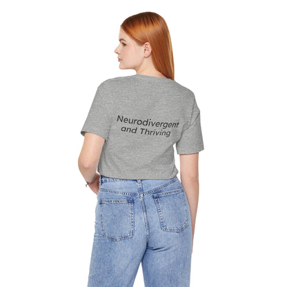 Person wearing a gray t-shirt with 'Neurodivergent and Thriving' text on the back, standing against a white background.