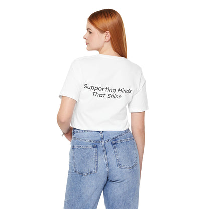Person wearing a white t-shirt with 'Supporting Minds That Shine' text on the back, standing against a white background.