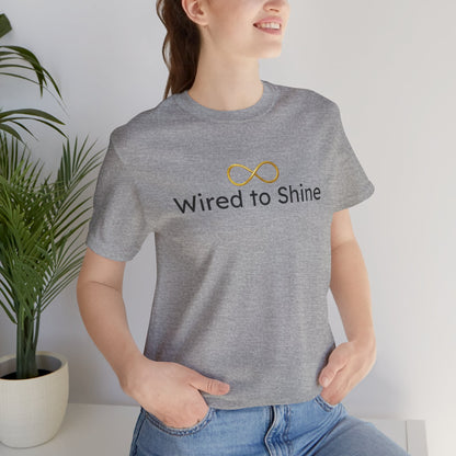 Person wearing a gray t-shirt with 'Wired to Shine' text and infinity symbol, standing indoors.