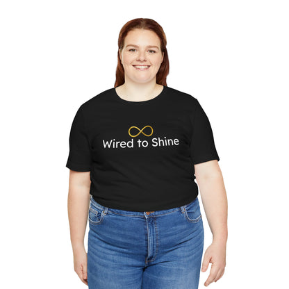 Person wearing a black t-shirt with 'Wired to Shine' text and blue jeans on a white background